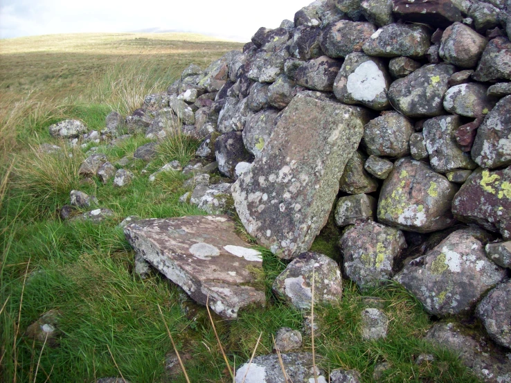 large rocks are stacked together in the grassy area