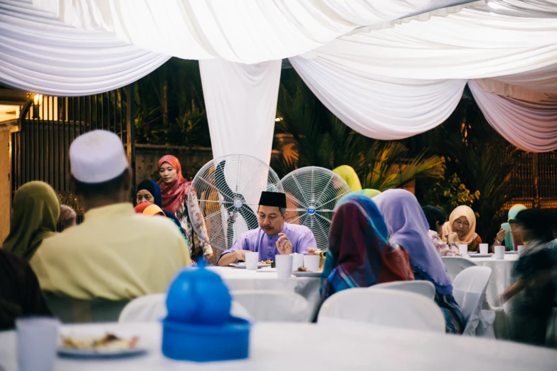 a group of people are sitting at tables eating