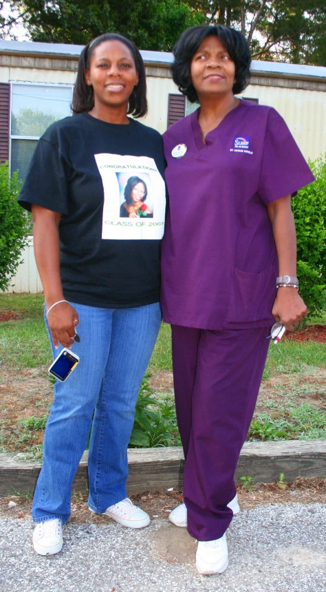 two women are dressed in scrubs standing near a building