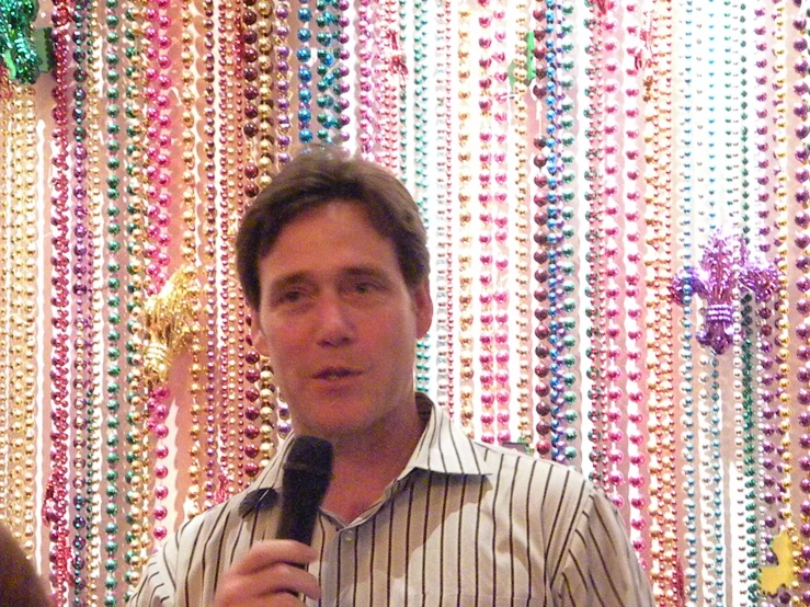 a man standing in front of colorful stringed wall with a microphone