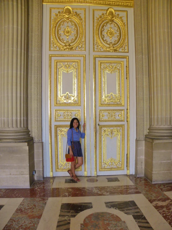 a lady standing in front of a very ornate door