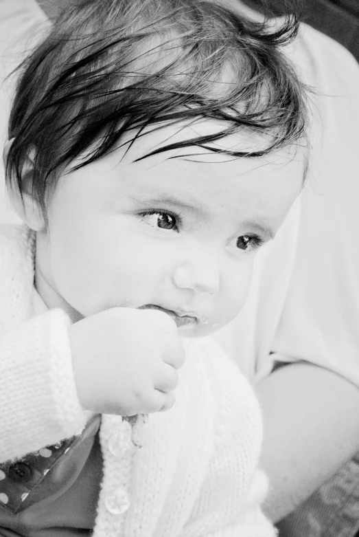 a young baby is chewing on an adult's hand