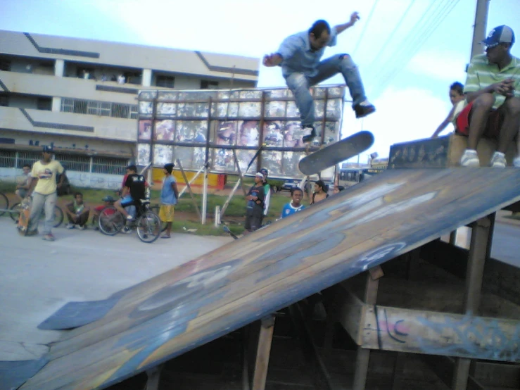 a skateboarder jumps over an obstacle and people watch