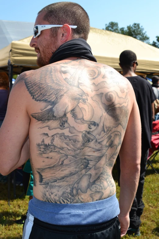 a man with a massive tattoo has a blue towel over his shoulders