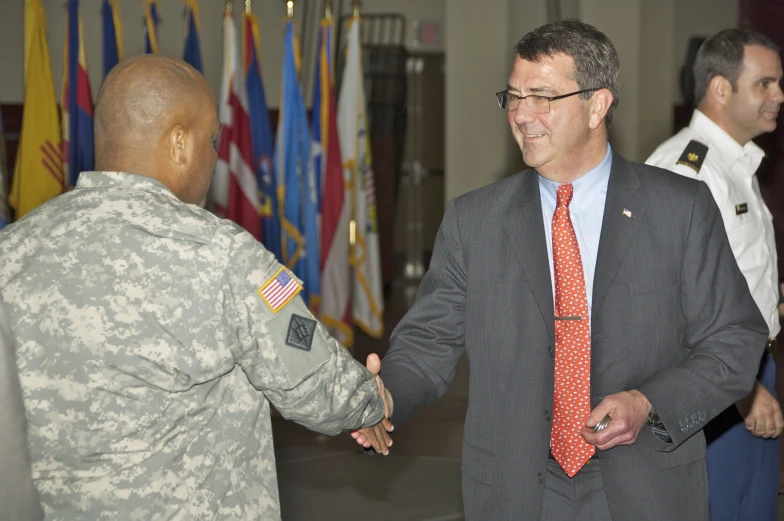 two military personnel meet at a banquet with one in suit and the other in red tie