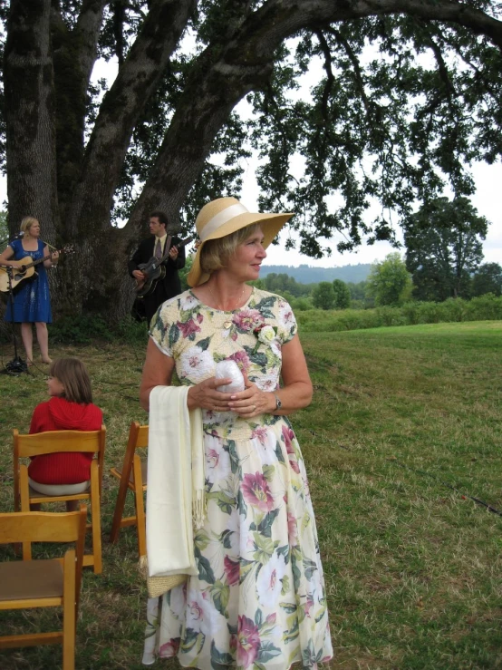 a woman holding her baby wearing a dress and a hat