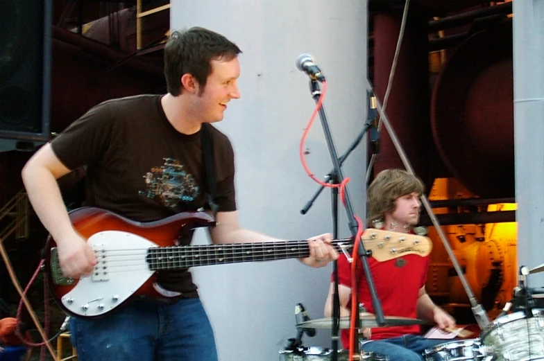 a man playing a guitar on stage with another band