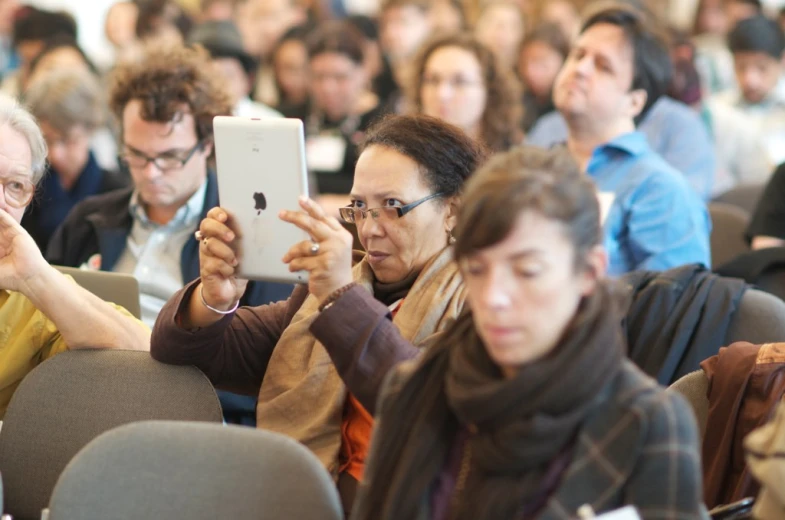 several people are sitting in a room using their cell phones