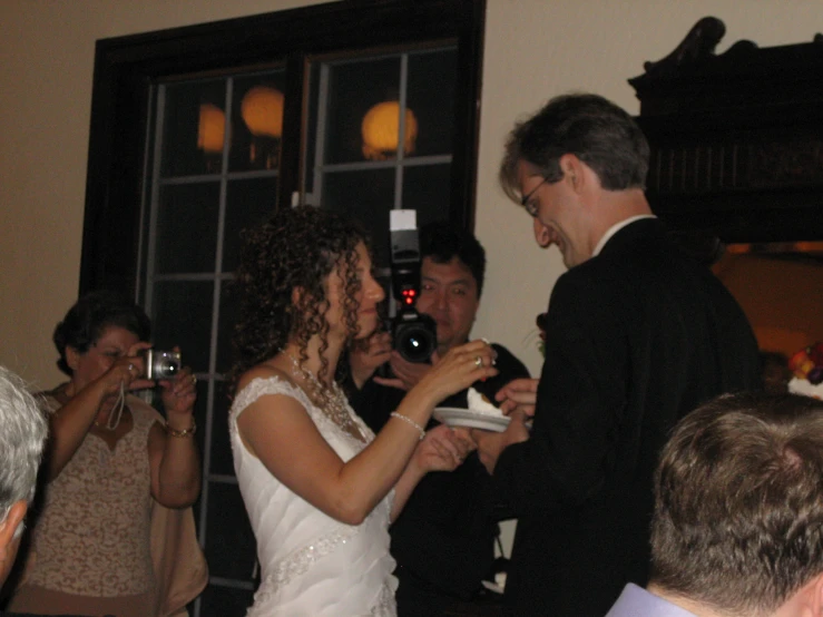 a bride and groom standing together with people behind them