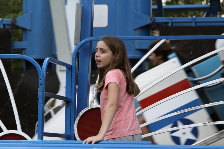 a girl stands in the background of an amut park ride