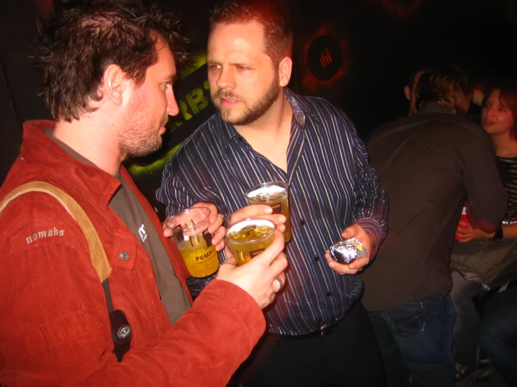 two men are looking at each other with beers in their hands