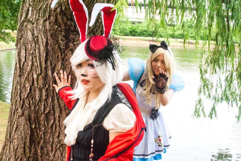 a pair of women standing next to each other in front of a tree