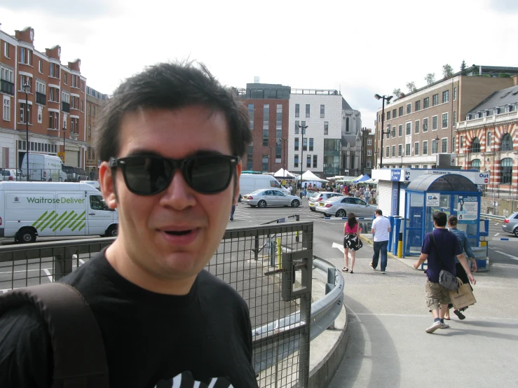 a man standing in front of a fence and a city street