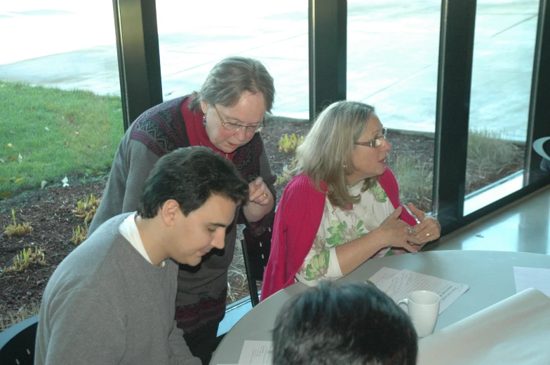 a group of people stand around a table