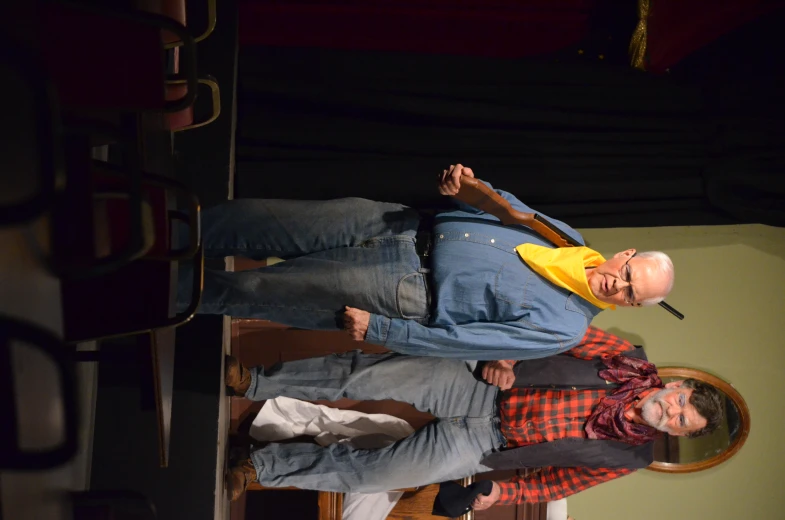 two men in old clothes stand on stage