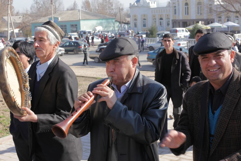 two men play musical instruments in front of a group