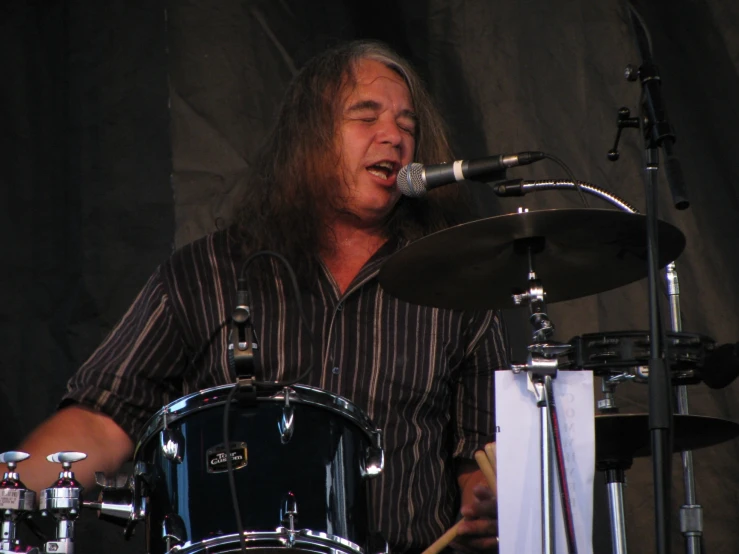 a man with long hair plays a drum set