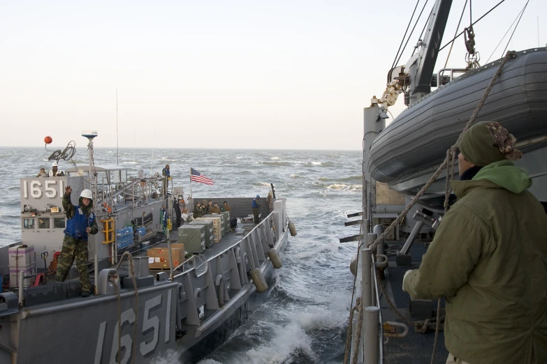 a man in a green jacket looking at another ship