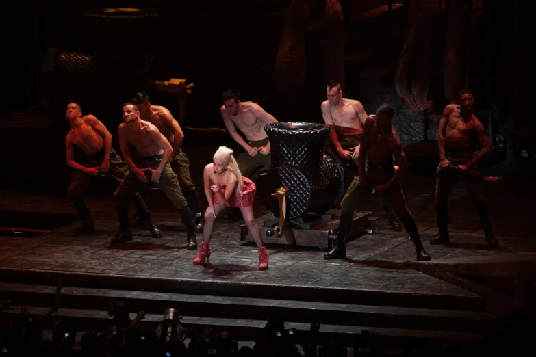 several  and tattooed men in performance with the woman standing on stage