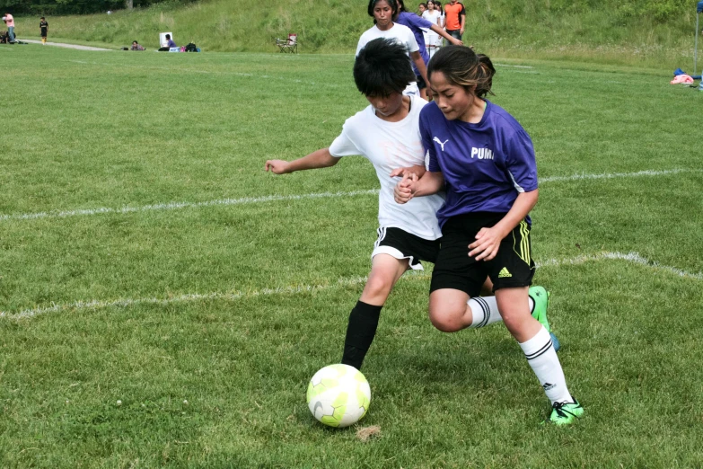 two young women playing soccer against each other