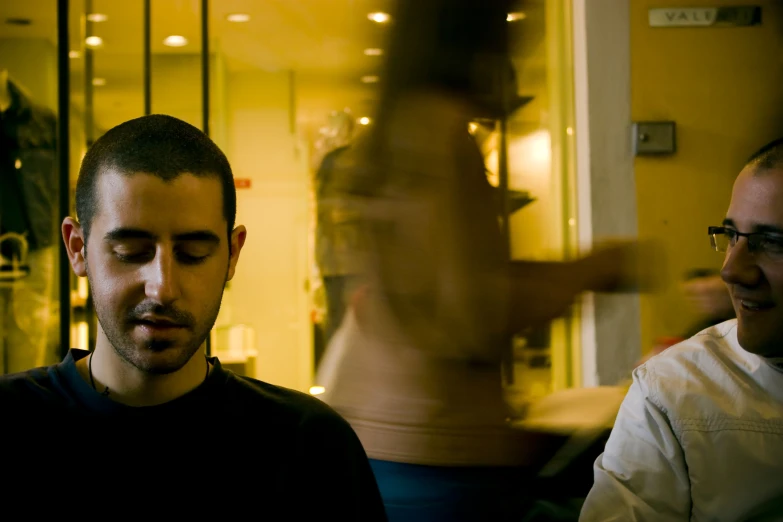 two men sit next to each other in front of a store window