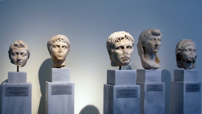 several ancient heads sit on pedestals near each other