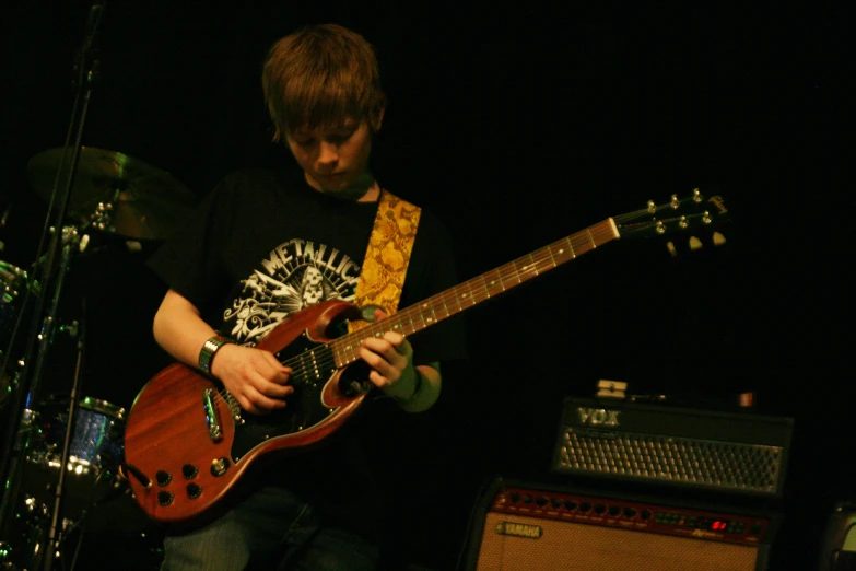 a man plays the guitar as a musical instrument looks on