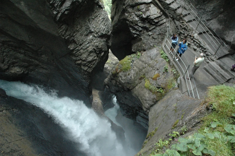 a waterfall is in the middle of two people looking up