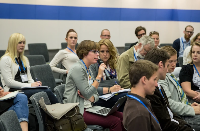 people sitting on chairs and working in a auditorium