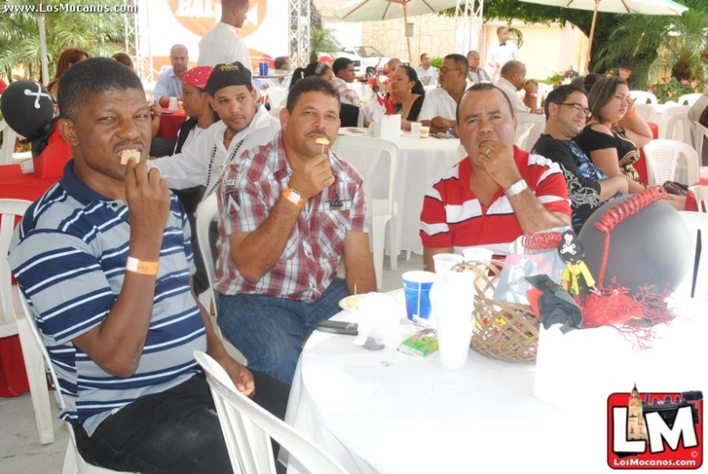 several men eating food while sitting down at a table