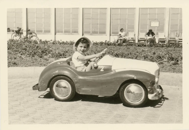 an old po of a little girl in a toy car