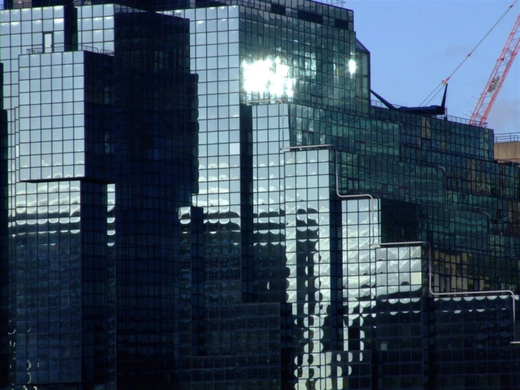 a tall building has many windows and a crane in the background