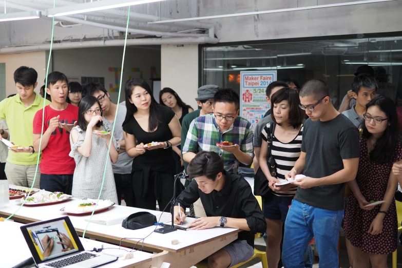 a number of people sitting at tables in a room with a laptop on it