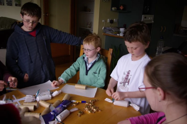 several children are around the table making small crafts