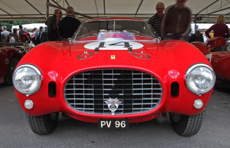 people look at vintage cars on display in a tent