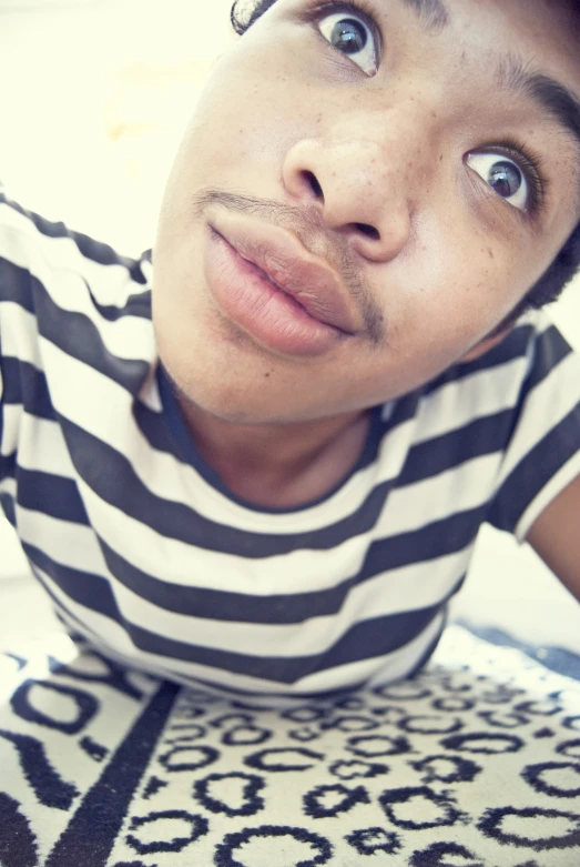 a young man with his eyes wide open laying on a carpet