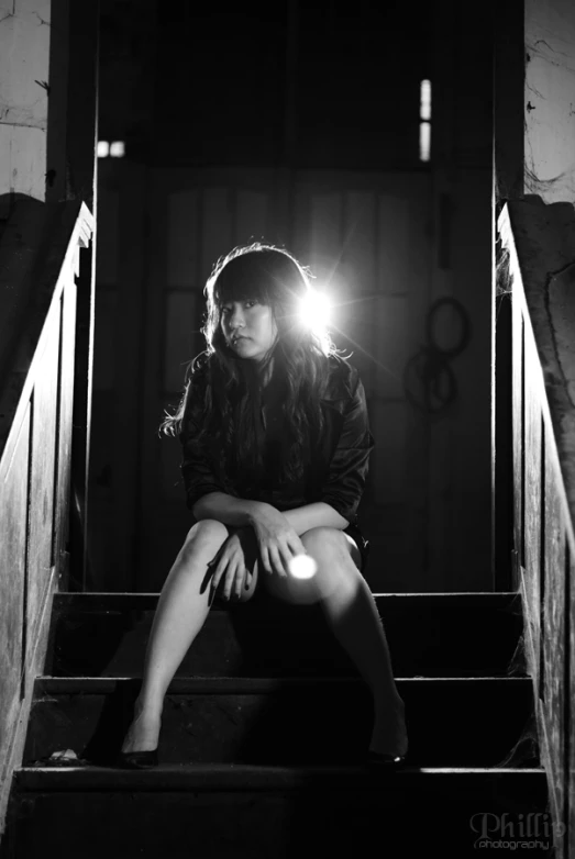 a woman sitting on stairs looking down at the floor