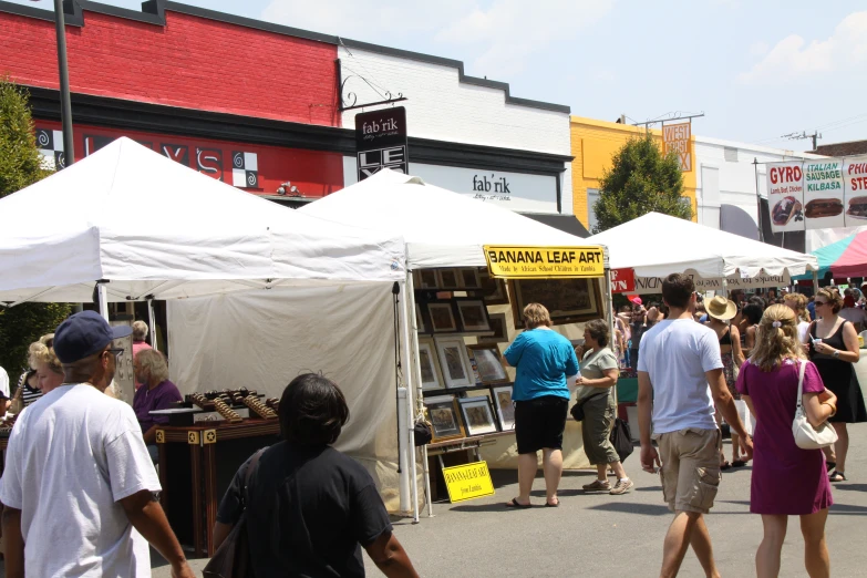 a crowd of people walking around tents next to buildings