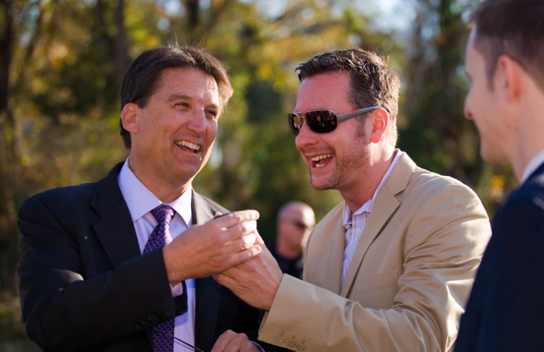 two men dressed in suits greeting one another with a smile