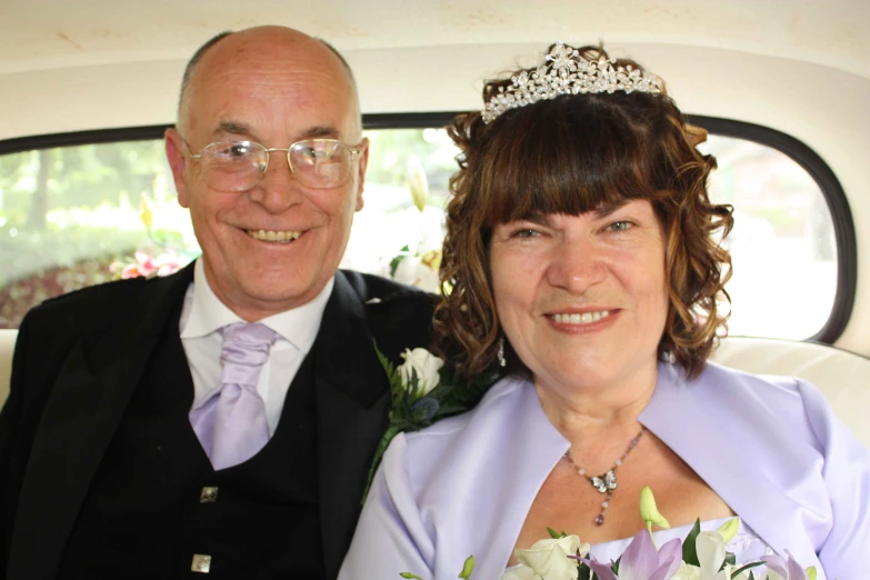 a bride and groom pose in the back of a car