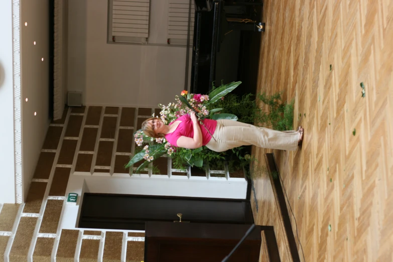 a woman in pink stands in front of a flower arrangement