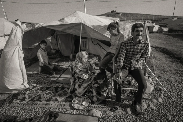 men sitting around a group of tents and a woman walking past them