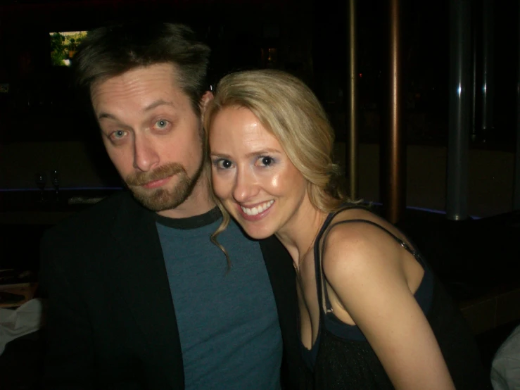 a man and woman pose for a picture in a dimly lit room