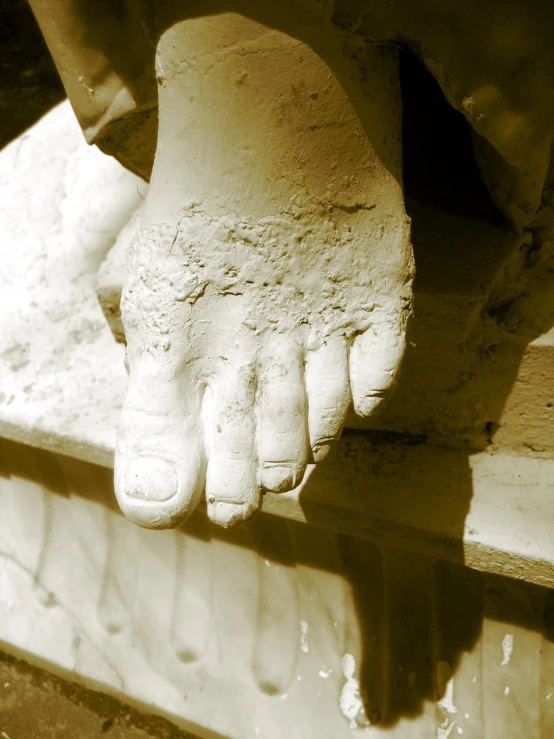 a foot on the bottom of a white pedestal