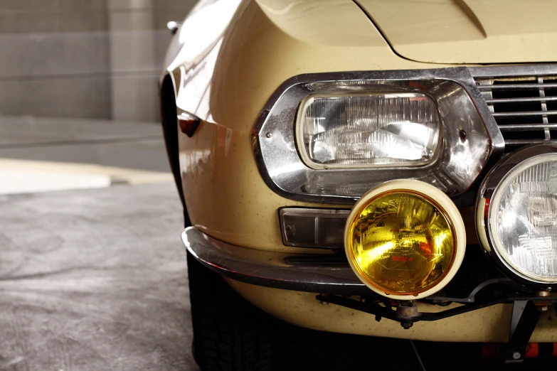 the headlights of a yellow classic car are on