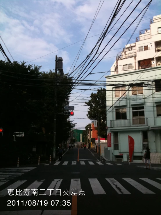 the crosswalk at an intersection with many electric wires above