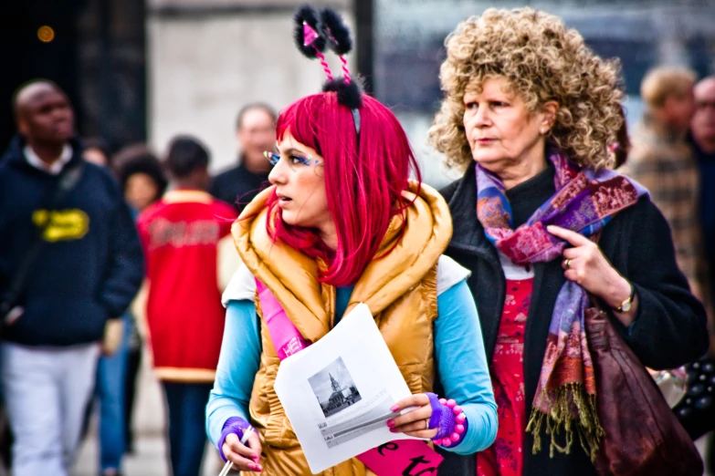 two women walk down the street in the midst of a crowd