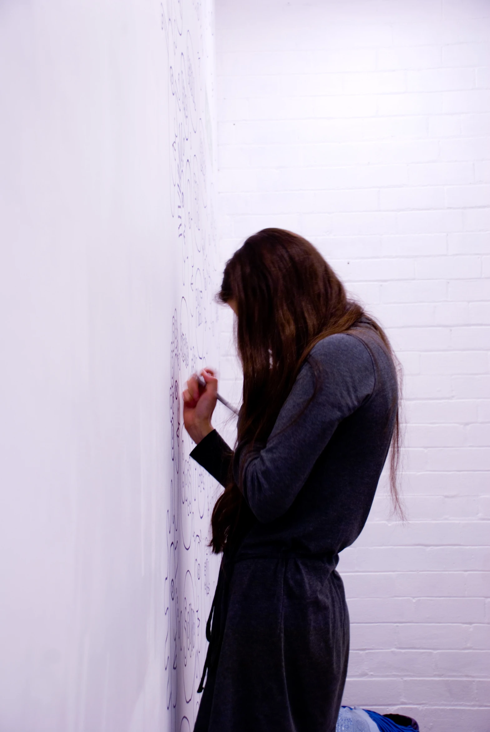 a woman is drawing on the wall while looking down