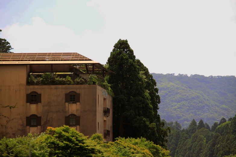 a building on the hill overlooking the mountains and trees