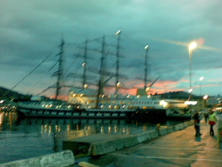 a large sailing vessel docked at a dock at dusk